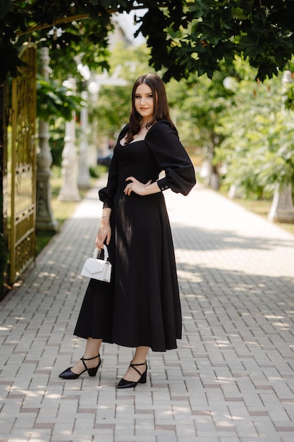 a woman in a black dress with a white handbag on the front