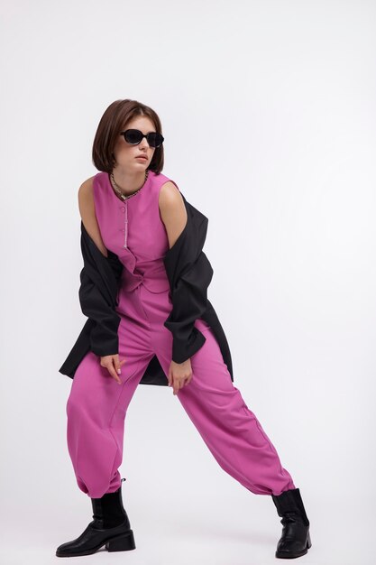 Woman in black jacket pink suit boots sunglasses on white background Bob haircut Studio Shot