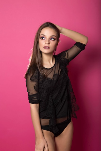 Woman in black lingerie on pink background