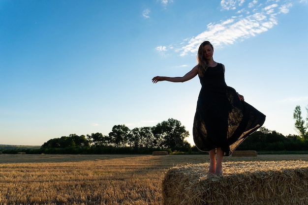 Woman in black long dress looking in camera standing in the field