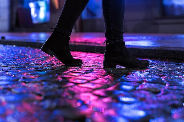 Woman in black shoes walking through the city street in the night