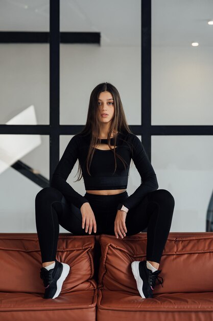 Woman in a black tracksuit sitting on sofa back