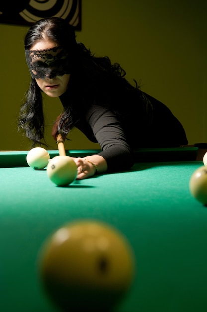 Woman in black veil plays billiards