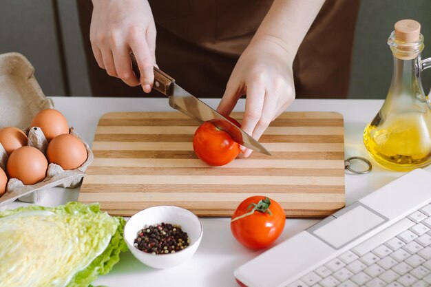 Woman blogger records dietary salad recipe on camera Online cooking lessons using laptop in kitchen