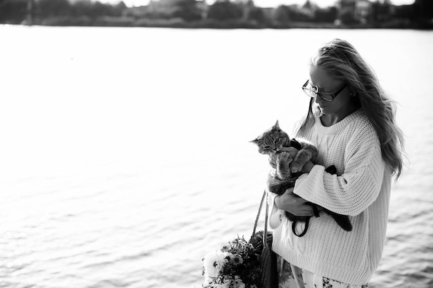 Woman blonde hugging a kitten on a walk