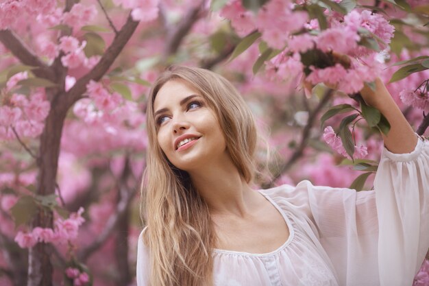 Donna all'albero sbocciante di sakura sulla natura