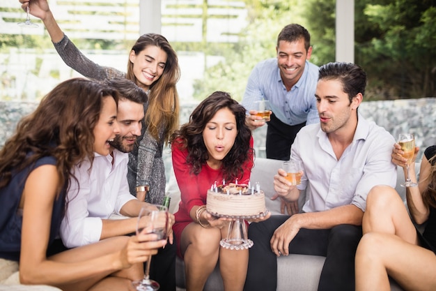 Woman blowing birthday candles with group of friends