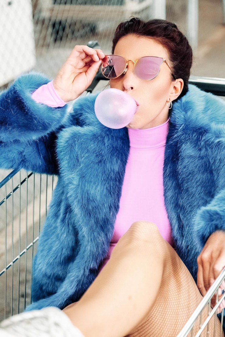 Photo woman blowing bubble gum while sitting in shopping cart