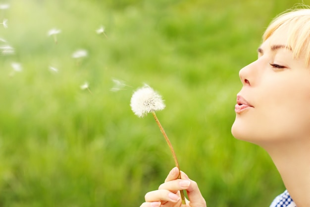 a woman blowing a dandelion over green background