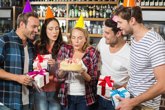 Woman blowing out candles while friends watch