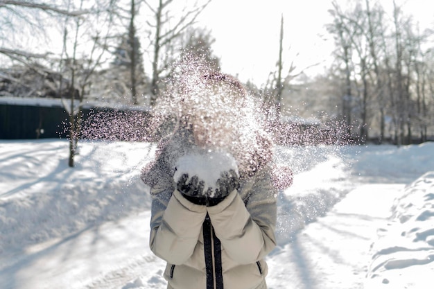 Foto donna che soffia la neve contro gli alberi