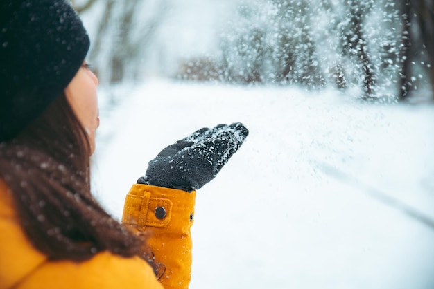 彼女の手から雪を吹く女性は、背景の冬の季節に公園を雪が降った