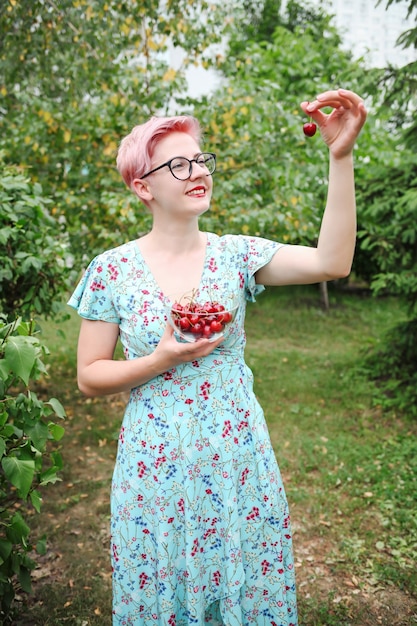 Woman in blue dress holding a handful of sweet cherries