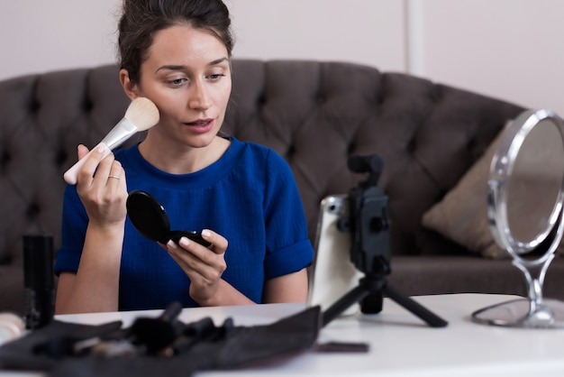 Woman in blue dress presenting a make up vlog