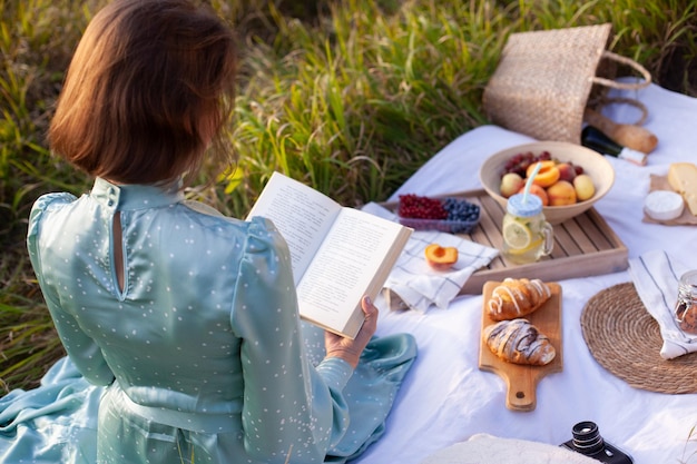 A woman in blue dress sits on a picnic in a park with panoramic view