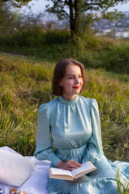 A woman in blue dress sits on a picnic in a park with panoramic view