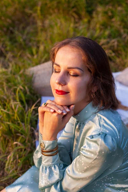 A woman in blue dress sits on a picnic in a park with panoramic view