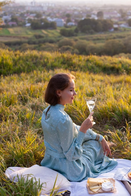 A woman in blue dress sits on a picnic in a park with panoramic view