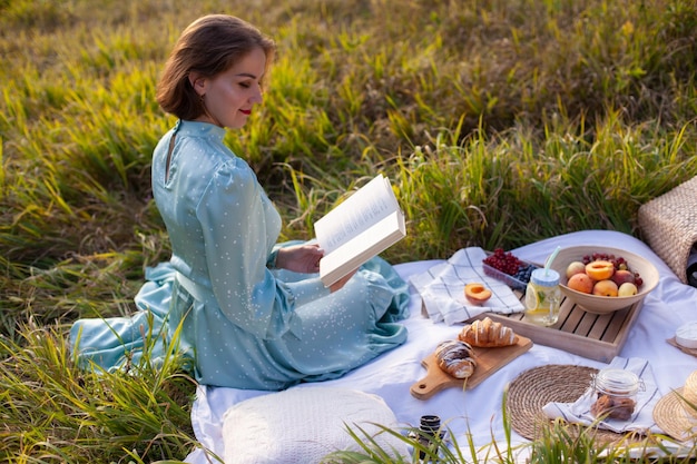 青いドレスを着た女性が、パノラマの景色を望む公園でピクニックに座っている