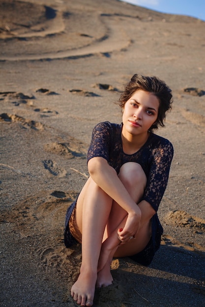 Woman in a blue dress sitting on a beach