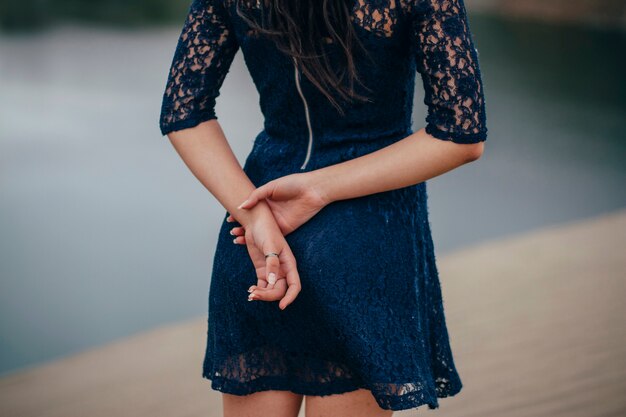 Woman in a blue dress standing near water