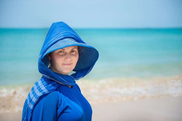 青い空と水の背景に青い帽子の女性。休暇の概念