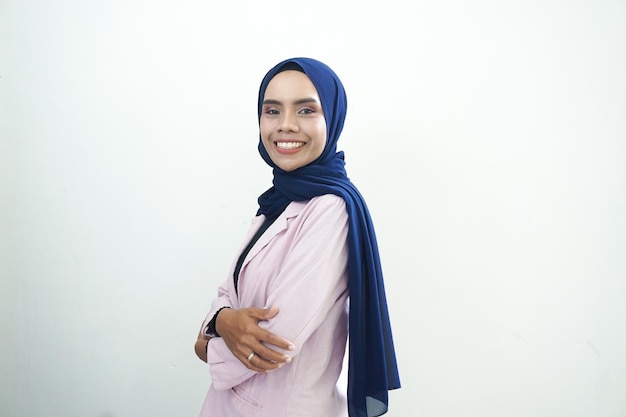 A woman in a blue hijab stands in a white room.