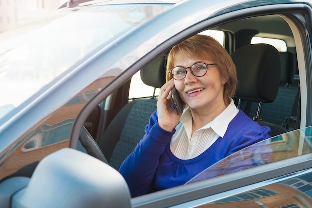 Una donna con una giacca blu alla guida di un'auto che attraversa la città