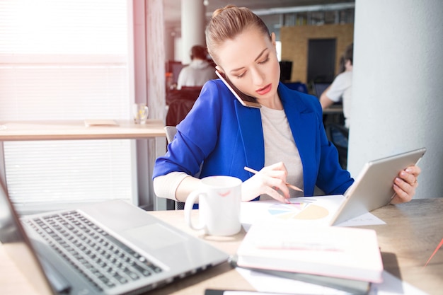 woman in blue jacket is sitting at the table and working