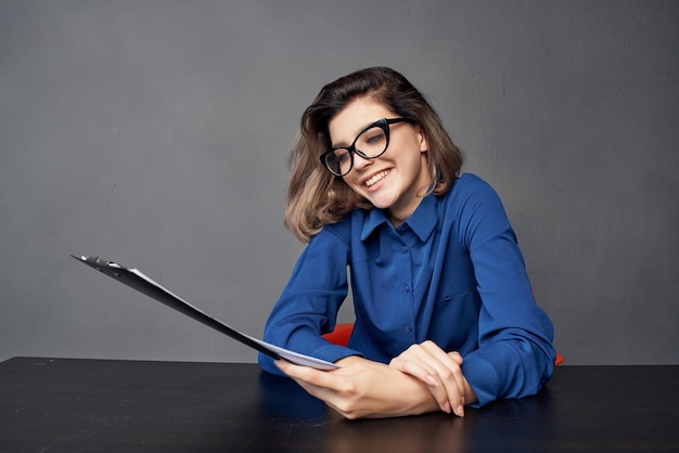 Woman in a blue shirt sits at the table folder in hands Copy Space