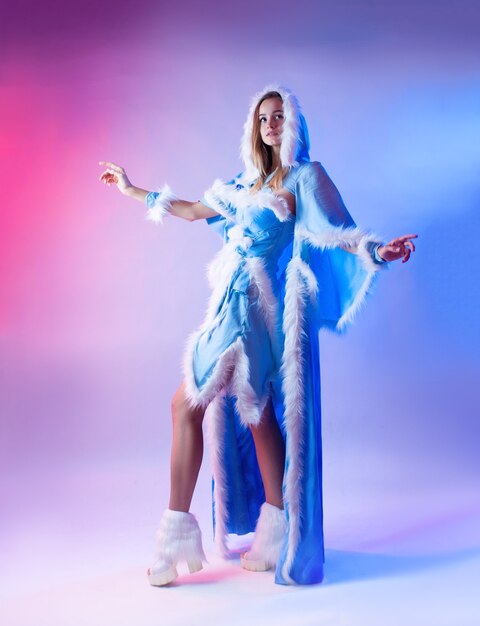 A woman in a blue snow maiden costume poses on a light neon background