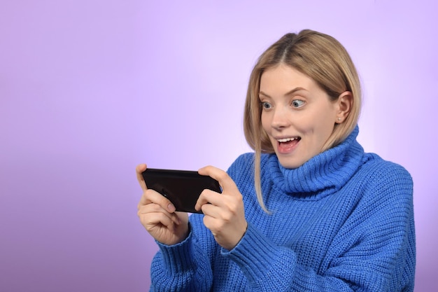 A woman in a blue sweater is playing on a tablet