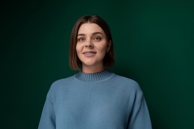 Woman in blue sweater standing against green background