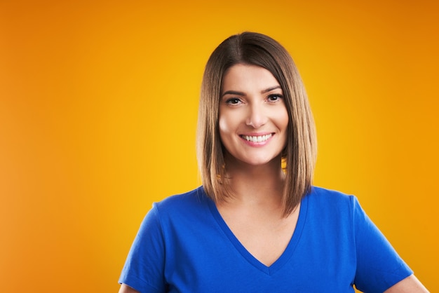 woman in blue t-shirt looking at camera over yellow background