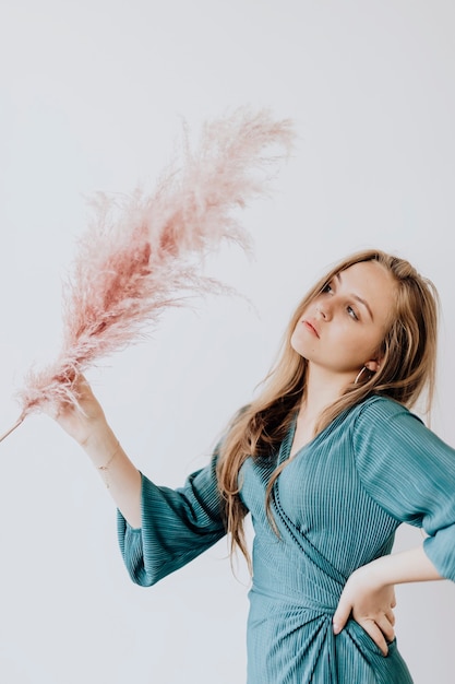 Photo woman in blue top holding pink grass