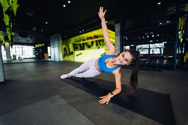 Woman in blue top and leggings practicing yoga performing