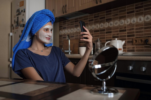 A woman in a blue towel on her head speaks via video link on a smartphone