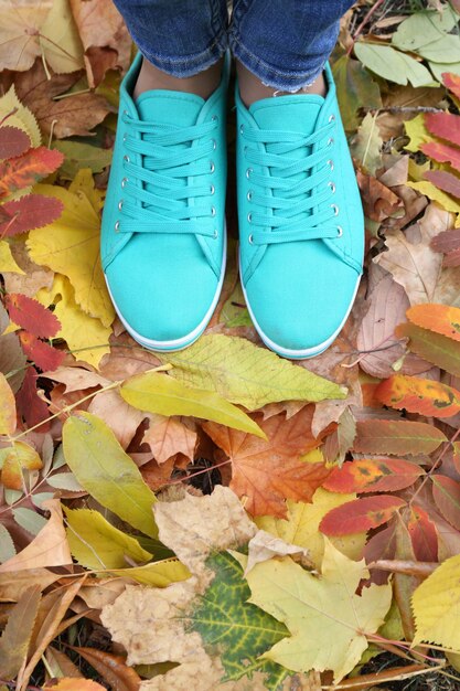 Woman in blue trainers standing on foliage