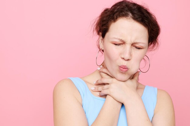 Woman in blue tshirt strangles herself emotions pink background