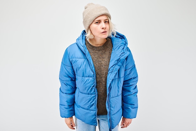 Woman in blue winter jacket and beanie against a light background