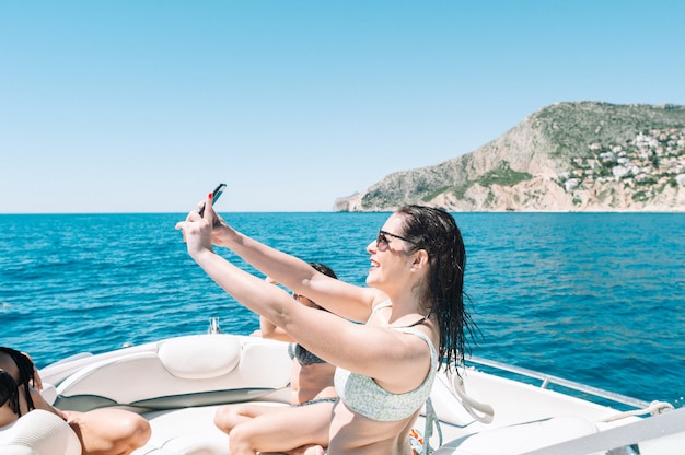 Donna in barca che si fa un selfie con uno smartphone