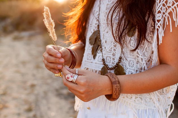 Foto donna in stile boho tiene una spikelet al tramonto