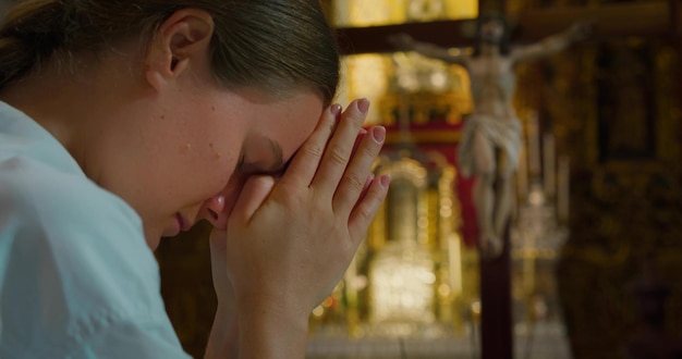女性は教会で神に祈りながら頭を下げた 女の子は救世主キリストに祈りかけて手を組んだ