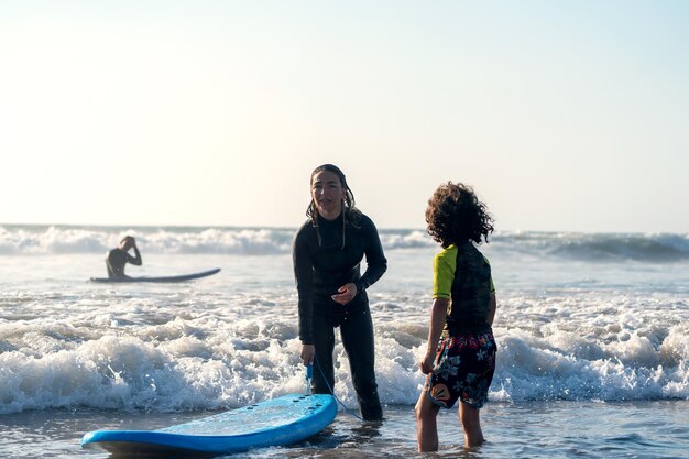 a woman and a boy in the water with a surfboard