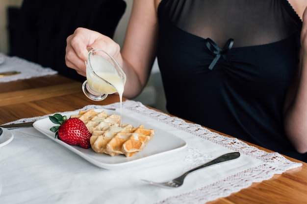 リビングルームでコーヒーテーブルとワッフルの女性の朝食