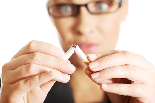 Woman breaking cigarette against white background