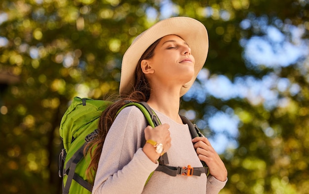 女性の息と自然の中でのバックパッキングは、穏やかで平和でリラックスした冒険のために旅行します リラックスした女性旅行者は、新鮮な空気の旅を楽しんだり、健康フィットネスやハイキングの日のために屋外を探索したりします