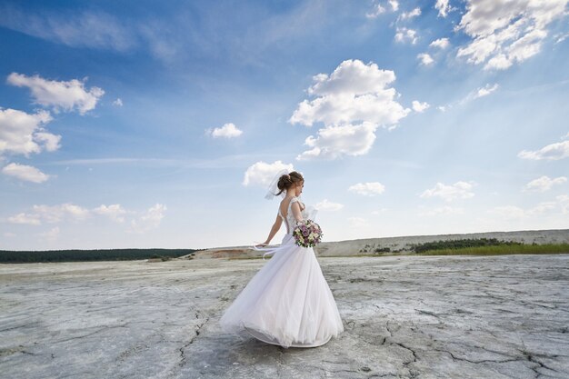 Woman bride in wedding dress in desert dancing