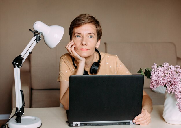 Woman in bright home office working laptop