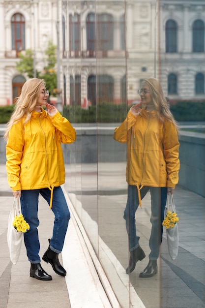 Женщина в яркой куртке на витрине в городе осенью